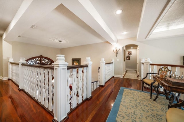 interior space featuring arched walkways, a textured ceiling, wood finished floors, and baseboards