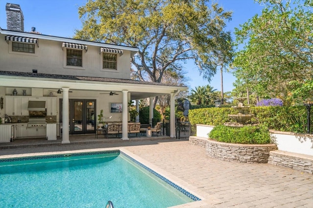 outdoor pool featuring french doors, grilling area, a ceiling fan, a patio area, and exterior kitchen