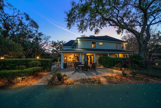 back of house at dusk featuring a patio area