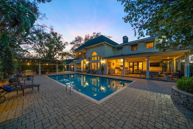 pool at dusk featuring a patio area and an outdoor pool