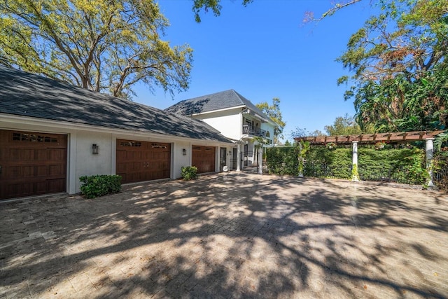 view of side of property featuring a garage, decorative driveway, and stucco siding