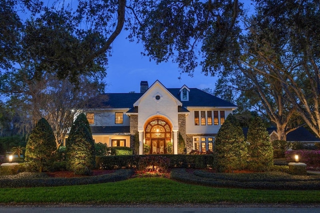 traditional home with french doors, a lawn, and a chimney