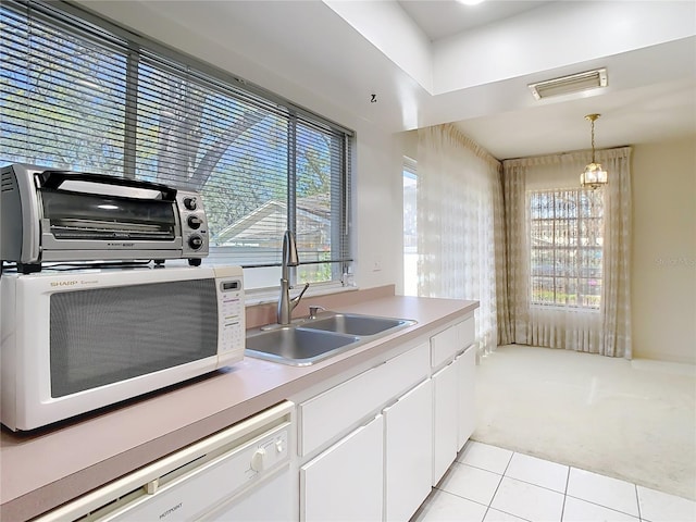 kitchen with visible vents, a healthy amount of sunlight, a sink, white cabinets, and white appliances