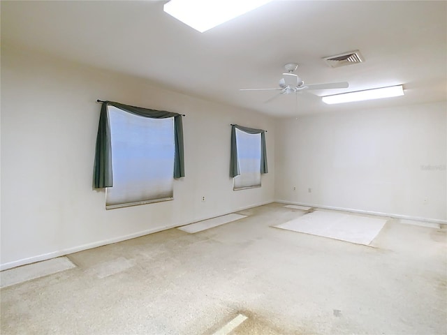 spare room with baseboards, visible vents, and a ceiling fan