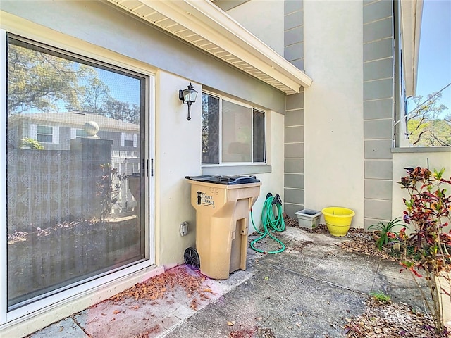 view of exterior entry with a patio and stucco siding