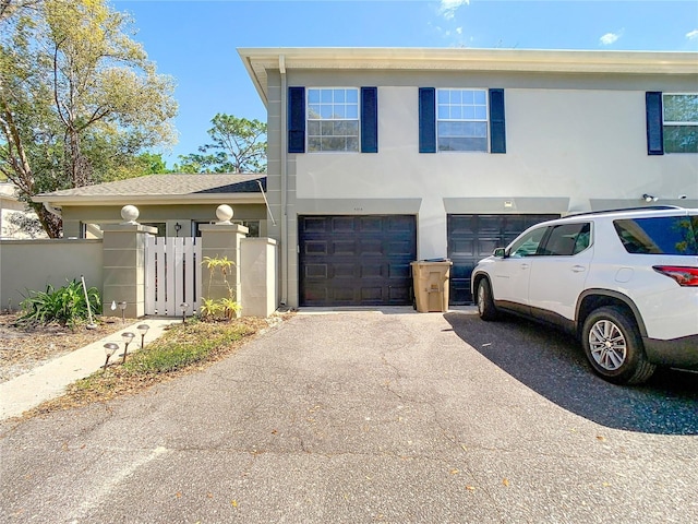 view of front of property with driveway, a garage, fence, and stucco siding