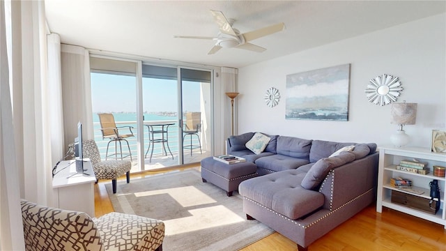 living area featuring a ceiling fan, a wall of windows, and wood finished floors