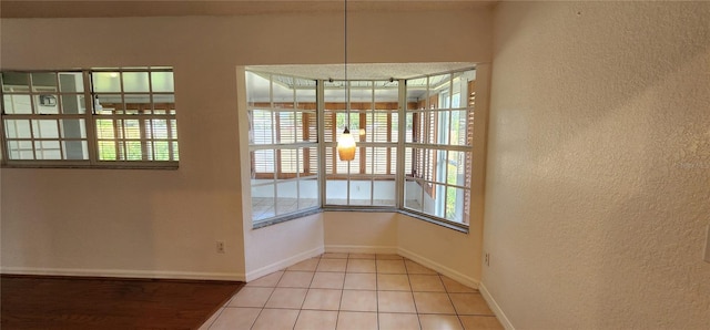 11722 Currie Ln Unit E1, Largo, FL 33774 - unfurnished dining area with a textured wall, baseboards, and tile patterned floors