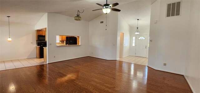 11722 Currie Ln Unit E1, Largo, FL 33774 - unfurnished living room with wood finished floors, a ceiling fan, high vaulted ceiling, and baseboards