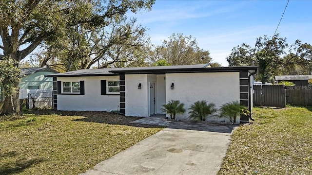 ranch-style house with fence, a front lawn, and stucco siding