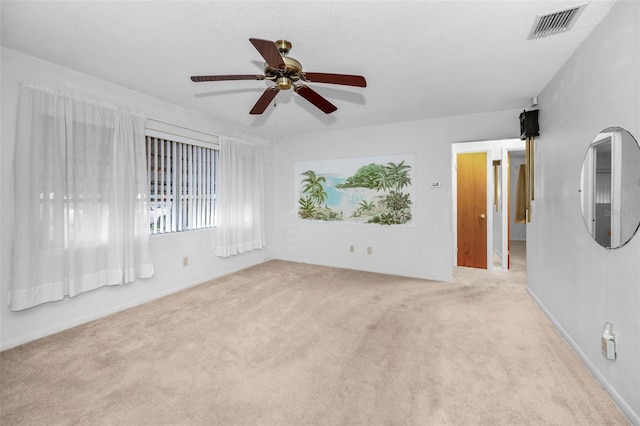 empty room featuring light carpet, a textured ceiling, visible vents, and a ceiling fan