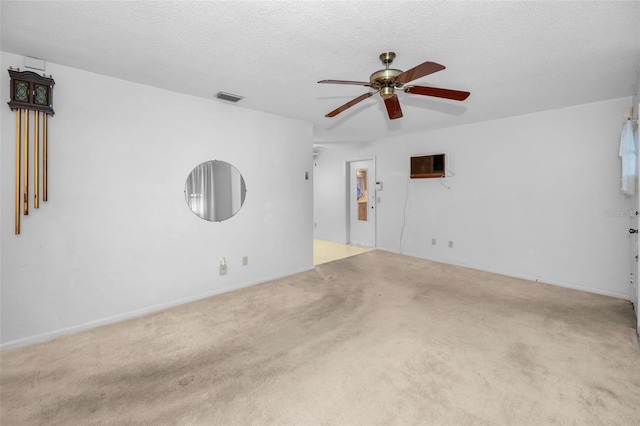 spare room with a textured ceiling, carpet flooring, and visible vents