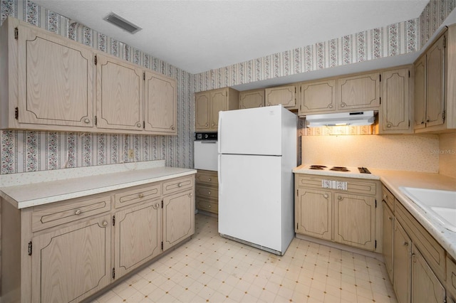 kitchen with wallpapered walls, white appliances, visible vents, light floors, and under cabinet range hood