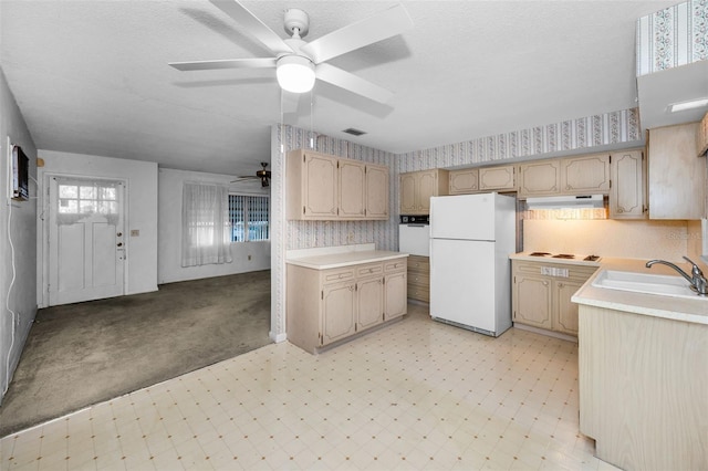 kitchen with under cabinet range hood, white appliances, a sink, light floors, and wallpapered walls