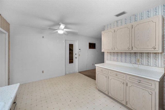 kitchen with wallpapered walls, visible vents, ceiling fan, light countertops, and light floors