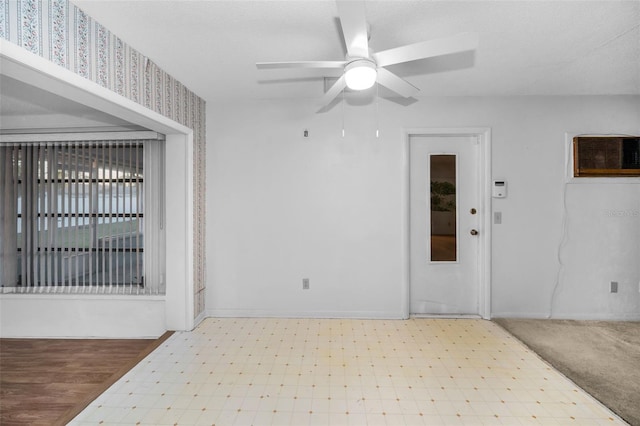 unfurnished room featuring baseboards, a wall mounted air conditioner, ceiling fan, and light floors