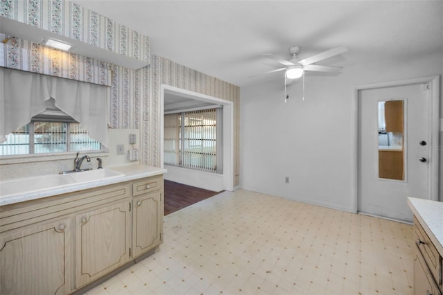 kitchen with a sink, light floors, light countertops, and wallpapered walls