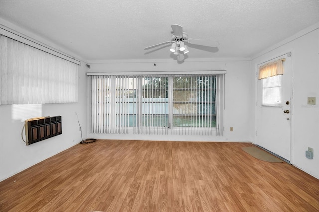 unfurnished living room featuring a textured ceiling, light wood finished floors, a ceiling fan, and heating unit