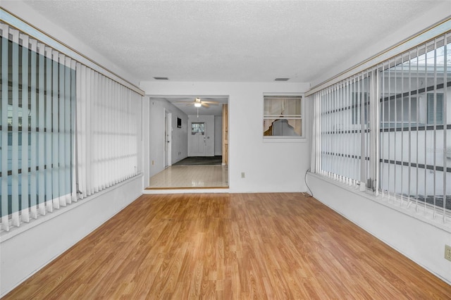 empty room with visible vents, ceiling fan, a textured ceiling, and wood finished floors