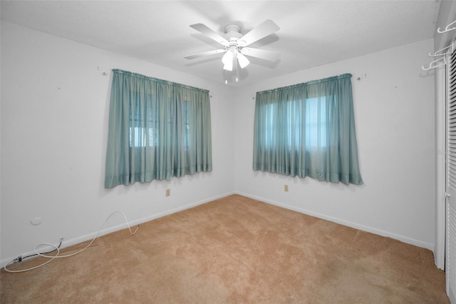 spare room featuring a textured ceiling, carpet, a ceiling fan, and baseboards