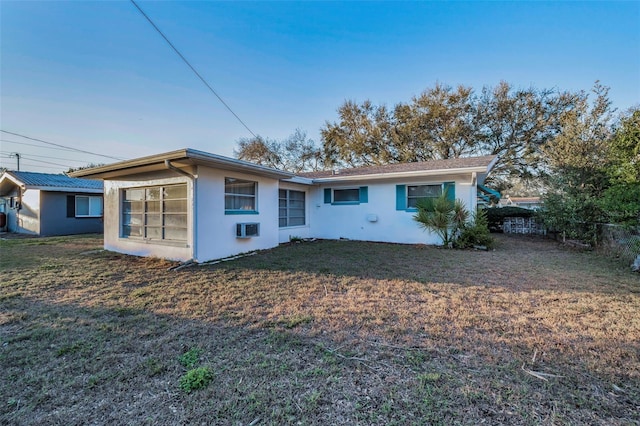 rear view of property featuring a yard, an AC wall unit, and stucco siding