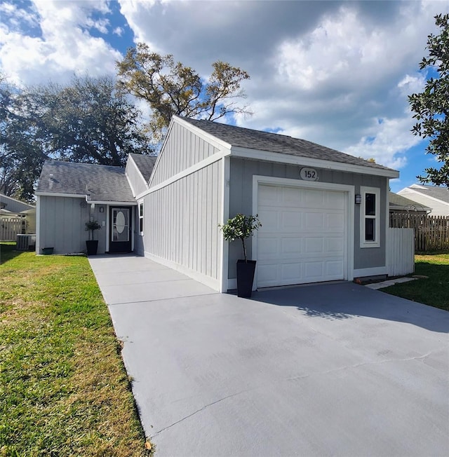 exterior space with board and batten siding, a front yard, fence, a garage, and driveway