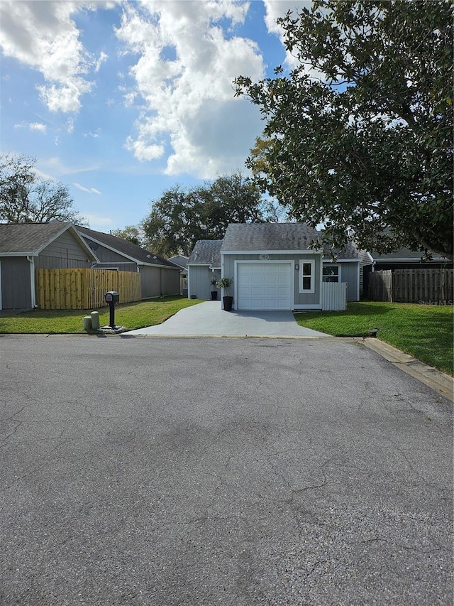 view of front of house featuring a garage, concrete driveway, a front yard, and fence