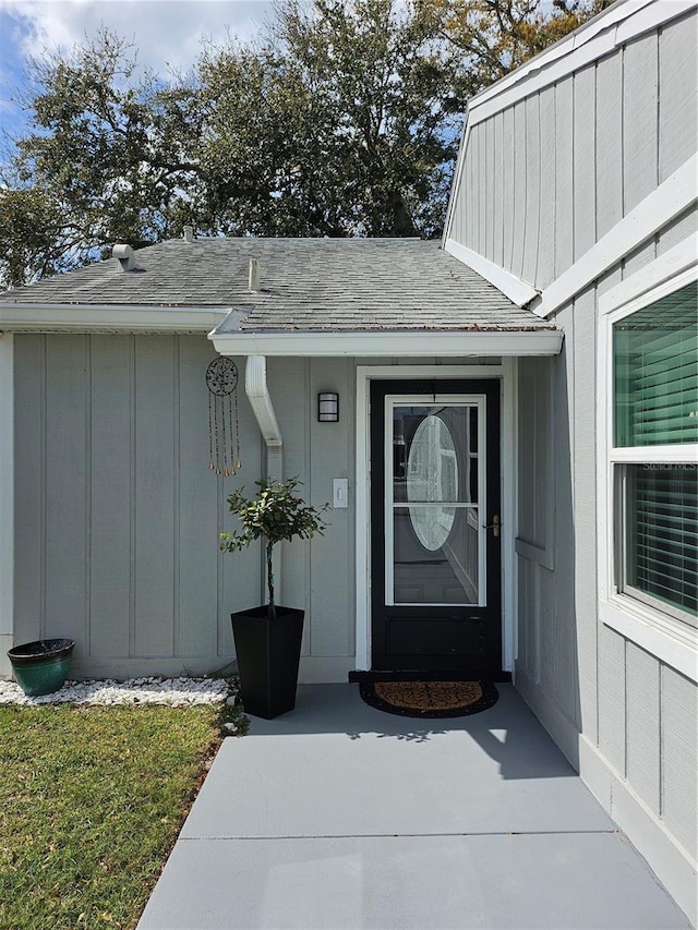 property entrance featuring a shingled roof and board and batten siding