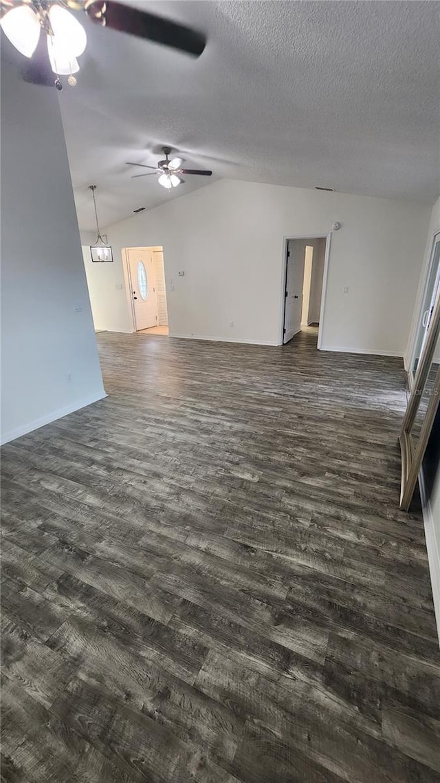 empty room with lofted ceiling, dark wood-style flooring, and a textured ceiling