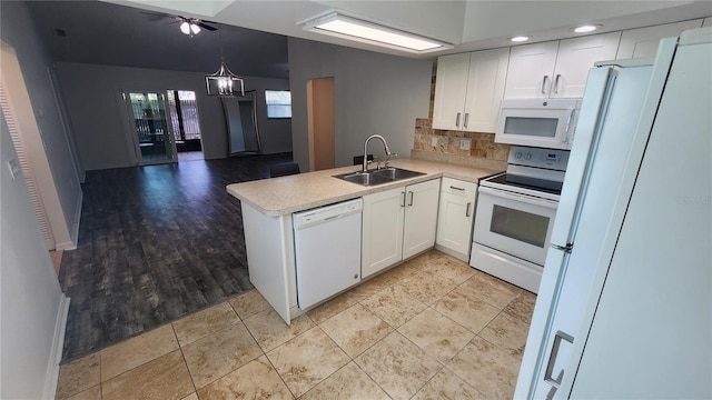 kitchen featuring white appliances, white cabinets, a peninsula, light countertops, and a sink