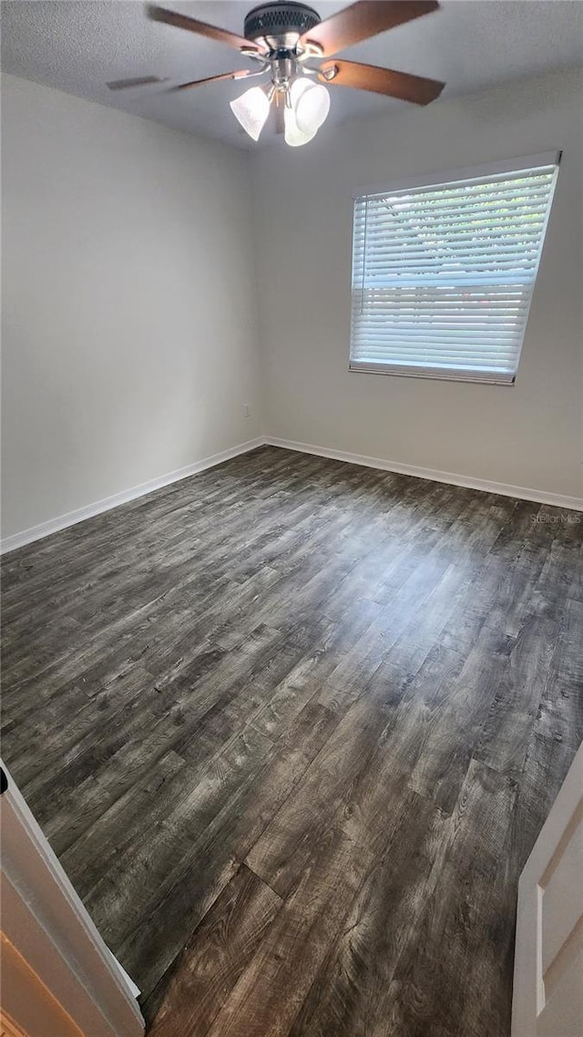 spare room featuring dark wood-style floors, a textured ceiling, a ceiling fan, and baseboards