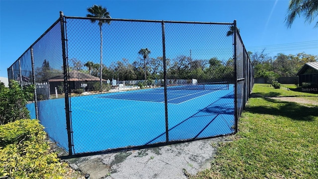 view of tennis court with fence and a lawn