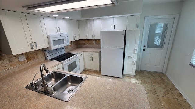 kitchen with white appliances, a sink, white cabinetry, light countertops, and tasteful backsplash