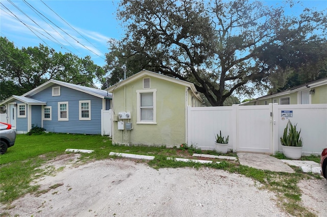 view of front of house with a front lawn, fence, a gate, and stucco siding