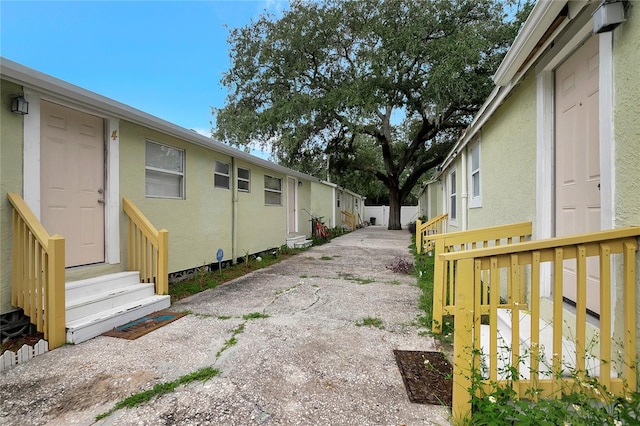 view of side of home featuring entry steps, fence, and stucco siding