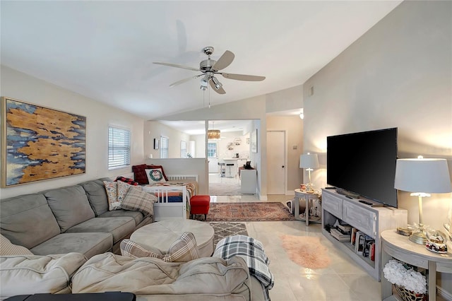 living room with a ceiling fan, vaulted ceiling, and light tile patterned floors