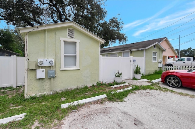 view of side of property with fence and stucco siding