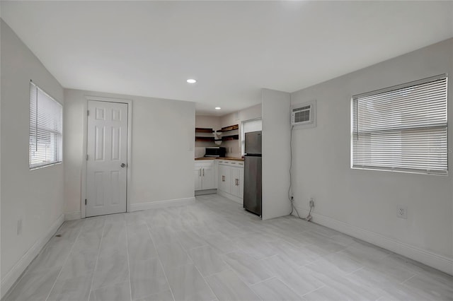 spare room with baseboards, an AC wall unit, and recessed lighting