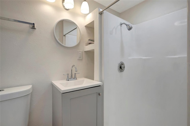 bathroom featuring a shower, vanity, and toilet