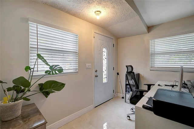 office area with a textured ceiling, light tile patterned flooring, and baseboards