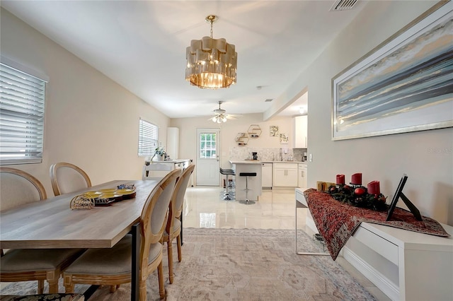 dining area with ceiling fan with notable chandelier and visible vents