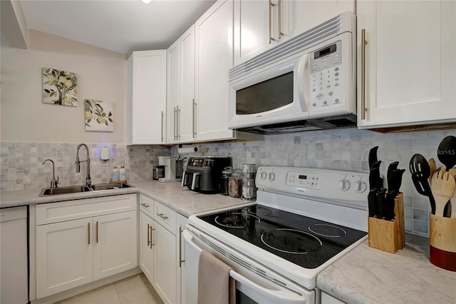 kitchen featuring white appliances, white cabinets, and a sink