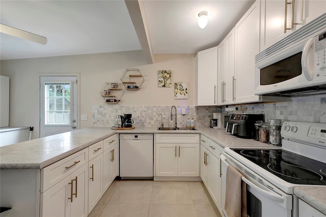 kitchen featuring white appliances, tasteful backsplash, a peninsula, light countertops, and a sink