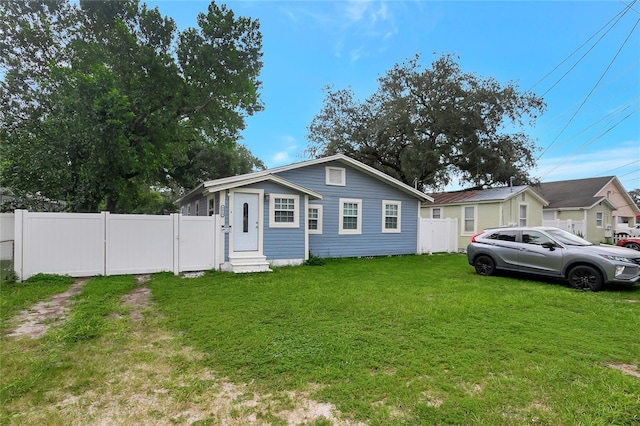 bungalow-style house with entry steps, fence, and a front lawn