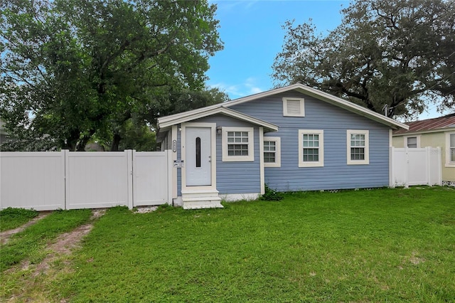 bungalow with entry steps, a front yard, fence, and a gate