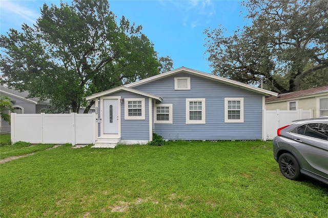 bungalow with entry steps, fence, and a front lawn