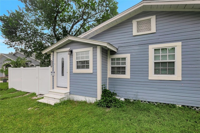 exterior space with entry steps, a lawn, and fence