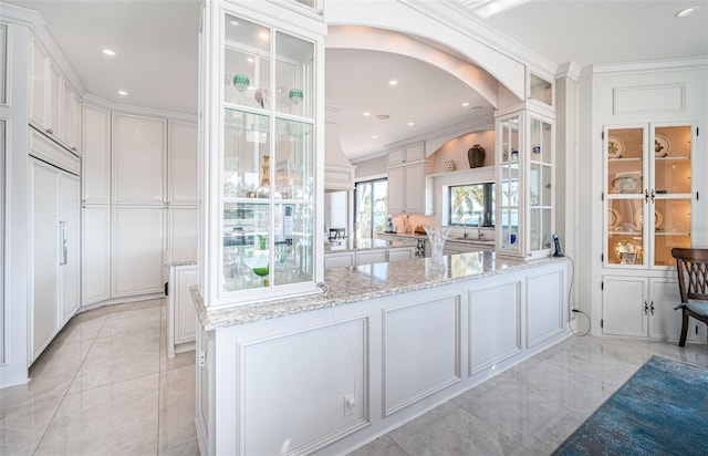 bar with ornamental molding, arched walkways, a decorative wall, and recessed lighting