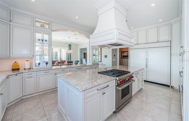 kitchen featuring white cabinets, custom exhaust hood, arched walkways, and premium appliances