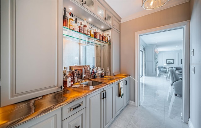 bar featuring crown molding, wet bar, marble finish floor, and a sink